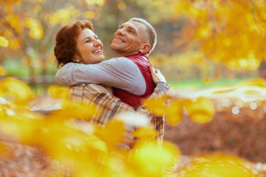Merhaba sonbahar. Gülümseyen romantik sevgili parkta sarılıyor..