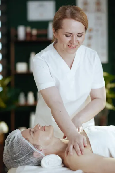 Healthcare time. massage therapist in spa salon massaging clients shoulder.