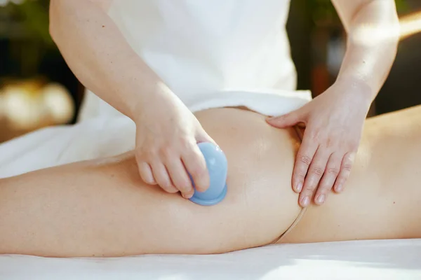 Healthcare time. Closeup on medical massage therapist in spa salon with vacuum therapy cup massaging clients buttocks.