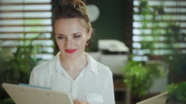 持続可能な不動産ビジネス 笑顔のスタイリッシュな40歳の女性リアクター キー付きの白いブラウスの現代緑のオフィス — ストック動画