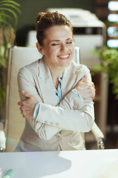 幸せな現代の小さなビジネスオーナーの女性は 現代のグリーンオフィスの軽いビジネスススーツで彼女自身を抱擁 — ストック写真