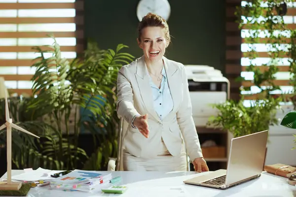 モダンなグリーンオフィスの軽いビジネスススーツで現代の小さなビジネスオーナーの女性を笑顔にし 握手を手渡す — ストック写真