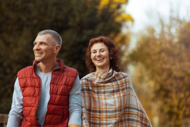 Merhaba sonbahar. Gülümseyen romantik aile parkta yürürken.