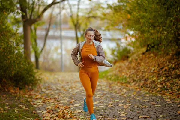 Merhaba sonbahar. Parkta spor kıyafetleri içinde zarif bir kadının tam boy portresi..