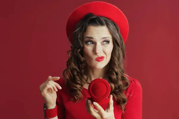 Happy Valentine. unhappy elegant woman in red dress and beret against red background with jewellery box.