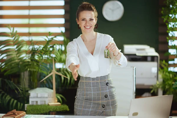 Time to move on. smiling elegant woman real estate agent in modern green office in white blouse with keys.