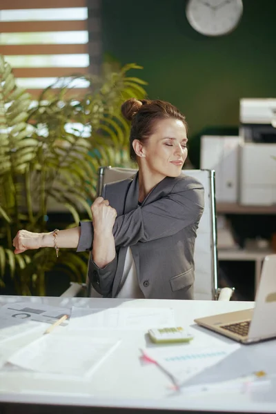 Sustainable workplace. smiling modern business woman in modern green office with laptop stretching hands.