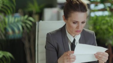 Yeni bir iş. Gri takım elbiseli, modern yeşil ofisteki orta yaşlı, üzgün kadın çalışanın işten çıkarılma mektubu..