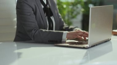 Sürdürülebilir iş yeri. Yeşil ofisteki gri takım elbiseli, dizüstü bilgisayarlı küçük işletme sahibi kadına yakın plan..