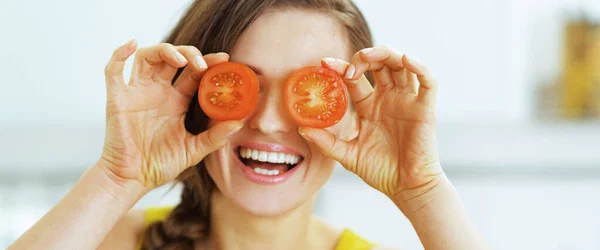快乐的年轻女子捧着两片番茄在眼前 — 图库照片