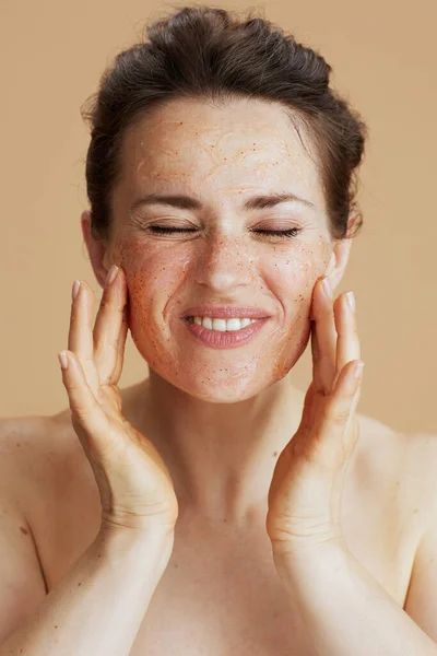 smiling young woman with face scrub isolated on beige.
