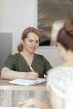 Sağlık hizmeti zamanı. Gülümseyen kadın masaj terapisti. Müşteri ve not defteri resepsiyonda..