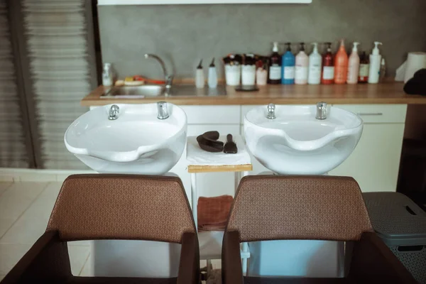 modern beauty salon with chairs, bottles of hair care products and salon backwash unit.