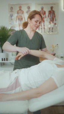 Sağlık hizmeti zamanı. Müşteri kontrollerini yaparken masaj dolabında mutlu kadın masaj terapisti..