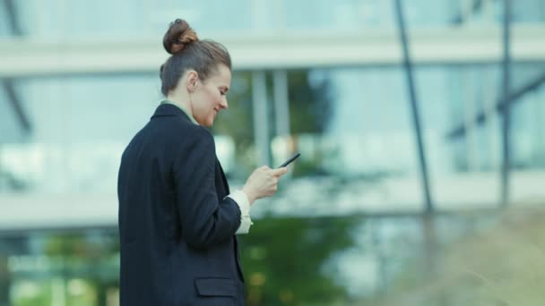 黒いジャケットのオフィスビル近くの女性労働者の後ろから見たブリーフケースウォーキング — ストック動画