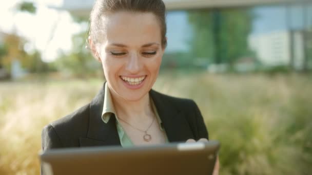 商务区内快乐的中年妇女穿着黑色夹克 使用平板电脑 — 图库视频影像