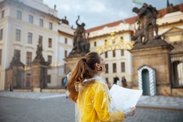 捷克共和国布拉格城堡附近身穿黄色上衣和雨衣的妇女身后看到的地图 — 图库照片