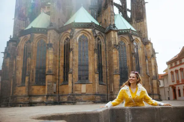 笑顔のトレンディな観光客の女性 黄色いブラウスとレインコート プラハチェコ共和国 — ストック写真