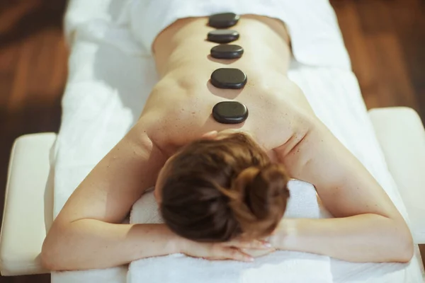 Healthcare time. relaxed modern woman in spa salon having hot stone massage and laying on massage table.
