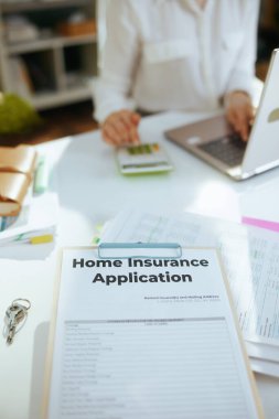 Eko emlak işi. Hesap makinesi, dosya ve belgeyle çalışan yeşil ofisteki, beyaz bluzlu kadın emlakçıya yakın plan..