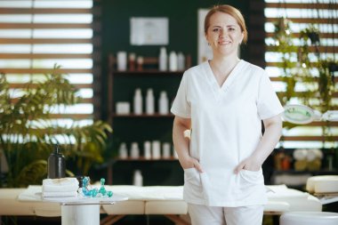 Sağlık hizmeti zamanı. Masaj dolabında kameraya bakan mutlu kadın masaj terapistinin portresi..
