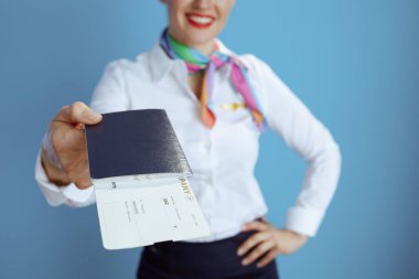 Uçuş biletleri ve pasaportuyla mavi arka plandaki mutlu ve zarif hostese yakın plan..