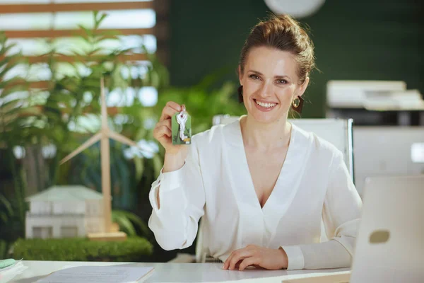Time to move on. smiling elegant middle aged business woman in modern green office in white blouse with keys.