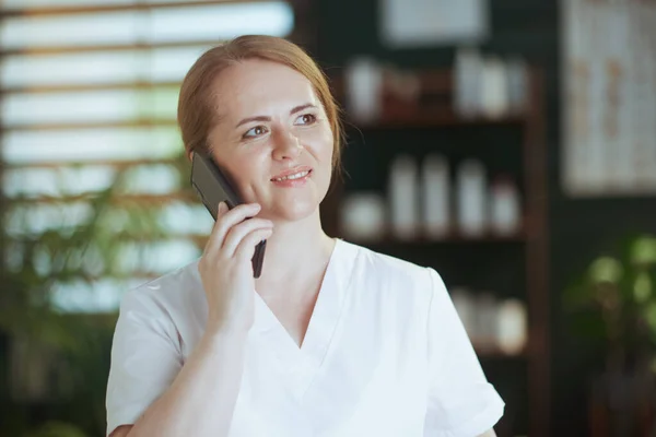 Healthcare time. happy massage therapist woman in spa salon using a smartphone.