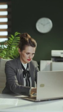 Sürdürülebilir iş yeri. Modern yeşil ofisteki gri takım elbiseli, küçük işletme sahibi 40 yaşında gülümseyen bir kadın..