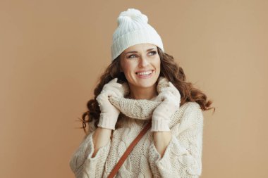 Merhaba kış. Bej kazaklı, eldivenli ve bej şapkalı mutlu modern kadın portresi..