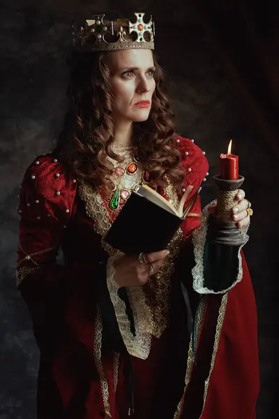 Pensosa Regina Medievale Abito Rosso Con Libro Candela Corona Sfondo — Foto Stock