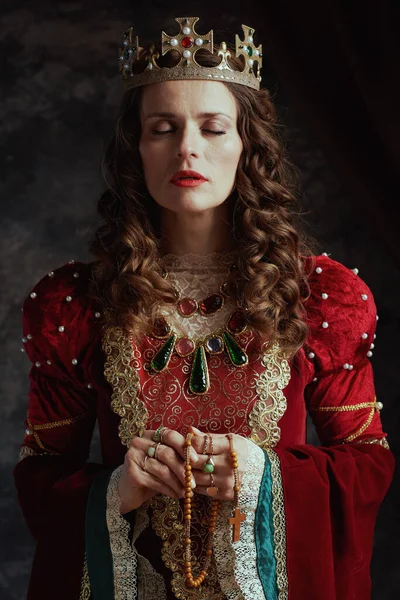穿着红衣服的中世纪女王 有念珠和冠冕 背景是深灰色的 — 图库照片