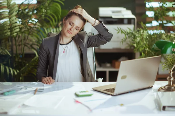 Sustainable workplace. smiling modern business woman at work with laptop stretching neck.