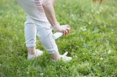 Yaz zamanı. Doğanın dışındaki çayırlarda itici sprey kullanan bir kadına yakın çekim..