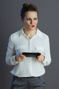 Modern 40 yaşında beyaz bluzlu küçük işletme sahibi kadın sosyal medyada gri üzerinde izole akıllı telefon kullanıyor..