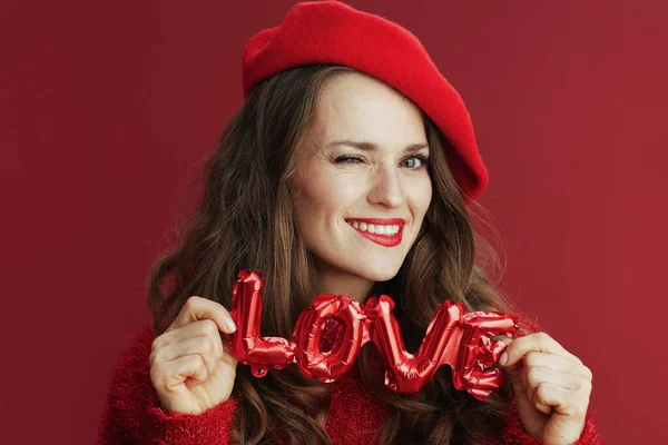 Happy Valentine. smiling elegant 40 years old woman in red sweater and beret with love inscription.