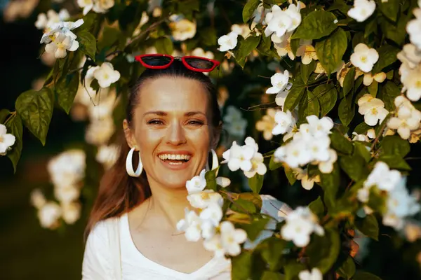 夏天的时候花树旁穿着白衬衫的快乐时尚女人的画像 — 图库照片