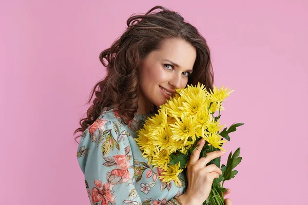 花蕾飘逸的中年妇女 一头长长的波浪般的黑发 黄色菊花 背景为粉色 — 图库照片