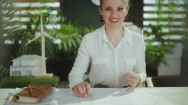 Sürdürülebilir emlak işi. Modern 40 yaşındaki kadın emlakçı, beyaz bluzlu, anahtarlı ve müşterisiyle tokalaşıyor..