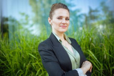 Siyah ceketli ve kollarını kavuşturmuş gülümseyen modern kadın işçinin portresi..