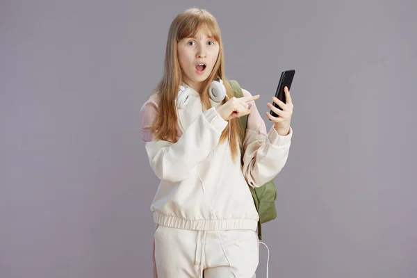 Surprised Modern Teen Girl Beige Tracksuit Backpack Headphones Using Smartphone — Stock Photo, Image