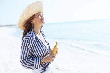 Deniz kıyısında güneş kremiyle gülümseyen zarif bir kadın..