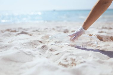 Plastik şişe toplayan deniz kıyısındaki çevreci eylemciye yakın çekim.