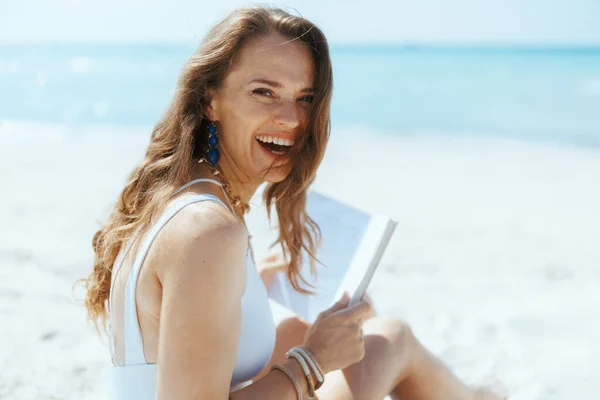 Usměvavá Stylová Žena Pláži Slaměným Sáčkem Knihou — Stock fotografie