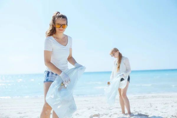 happy environment activists on the ocean shore with garbage bags collecting waste.