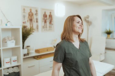 Sağlık hizmeti zamanı. Masaj dolabında gülümseyen kadın masaj terapisti.