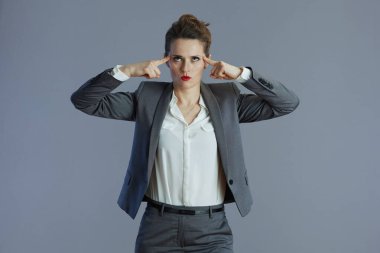 Gri arkaplana karşı gri takım elbiseli orta yaşlı trend iş kadını.