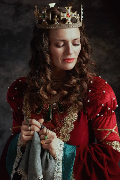 sad medieval queen in red dress with handkerchief and crown.