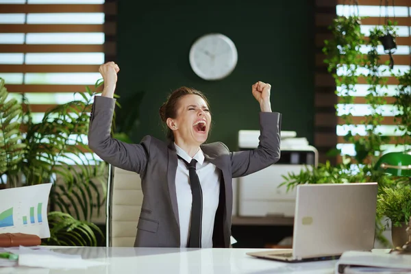 新しい仕事 モダンなグリーンオフィスの現代女性従業員を笑顔でグレービジネスススーツにノートパソコン投げ文書 — ストック写真