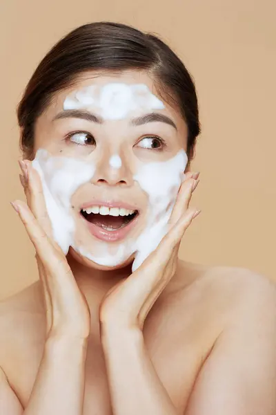 modern asian woman washing face on beige background.